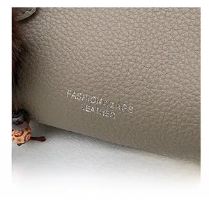 Détail de sac à main gris en cuir grainé avec marquage argent et pendentif perle