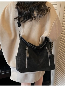Large black suede crossbody bag with decorative silver zippers shown on a model