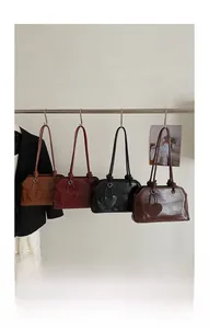 Detail view of four leather tote bags in classic colors with heart pendants and knotted straps