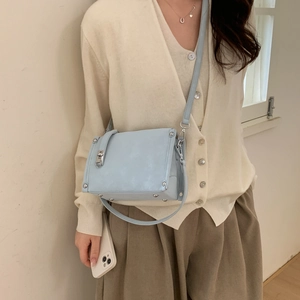 Detail of light blue PU leather crossbody bag with silver twist lock and adjustable strap