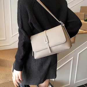 Detail of light brown lychee textured leather shoulder bag with silver rectangle buckle