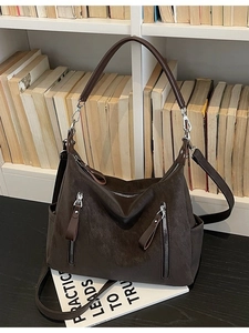 Deep brown large-capacity crossbody bag with silver zippers shown on a white bookshelf