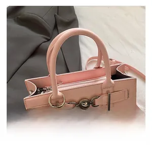 Gros plan d'un sac à main rose en cuir grainé avec boucle cœur et breloque lapin