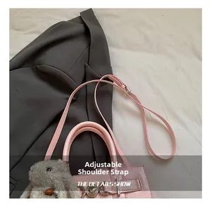 Détail d'un sac en cuir rose avec bandoulière réglable et pendentif lapin mignon