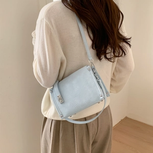 Side view of light blue crossbody pillow bag with pleated texture and silver twist lock