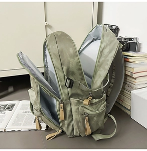 Détail du sac à dos vintage vert gris montrant plusieurs compartiments zippés et sa capacité