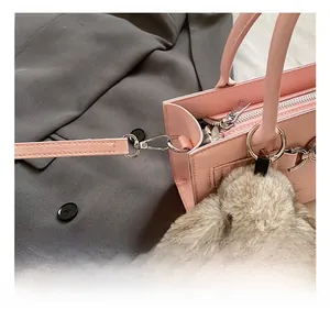 Gros plan du sac en cuir rose avec boucles argentées et breloque lapin en peluche