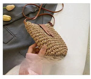 Detail showing hand-woven straw bag with premium brown leather strap and metal buckle closure