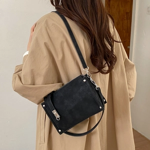 Detail showing the vintage matte texture and silver rivet hardware of the black crossbody bag
