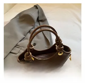 Detalle de bolso bucket de cuero marrón oscuro con asas redondas y herrajes dorados