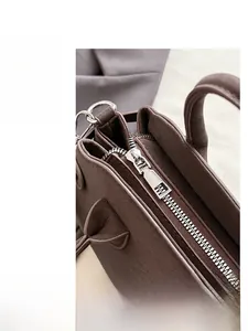 Detailed close-up of premium metal zipper and fine leather texture on dark brown baguette bag
