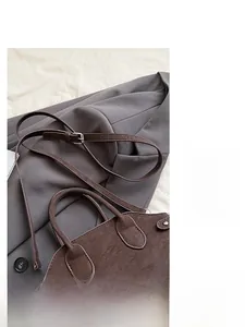 Detail of dark brown leather shell bag with adjustable thin strap and silver metal buckle