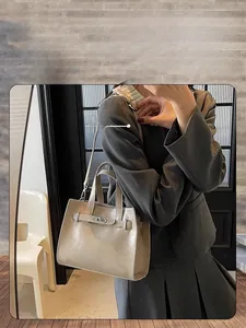 Detailed side view of beige leather tote bag with classic metal buckle and sturdy handle