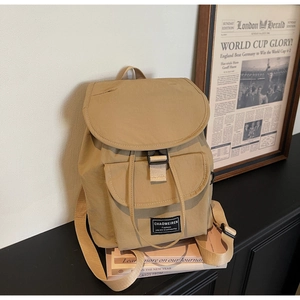 Detail view of khaki nylon backpack featuring front buckle pocket and woven texture