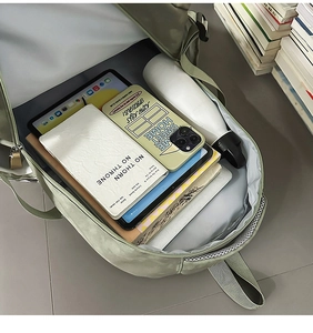 Vue intérieure du sac à dos vert montrant le rangement pour livres et tablette