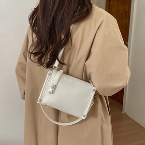 Detail of white pleated leather crossbody bag with silver studs and metal buckle on model