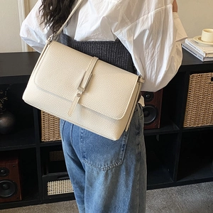 Detailed view of the lychee-textured leather surface and silver buckle on this square bag