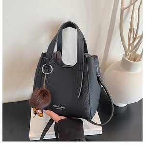 Détail du sac à main en cuir grainé noir avec pompon marron et accessoires de perles