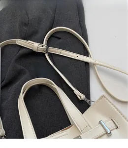 Detail view of smooth off-white PU leather bag with adjustable strap and metal hardware