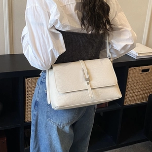 Detailed back view of off-white lychee grain leather crossbody bag with silver hardware