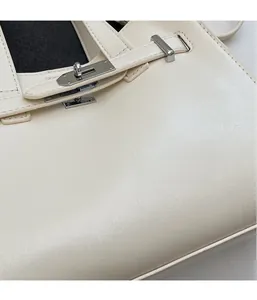 Detail of off-white leather handbag showing the silver metal turn-lock and fine stitching