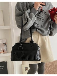 Detail of black glossy shoulder bag with heart pendant and retro doctor bag closure
