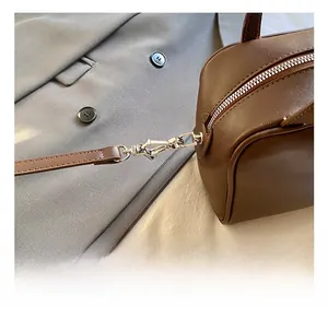 Detail of silver metal rotating hook and zipper on dark brown leather shoulder bag