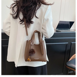 Détail du sac en cuir marron motif litchi avec pompon et breloque en perles de bois