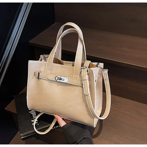 Detail of cream leather tote bag with silver twist lock on wooden stairs