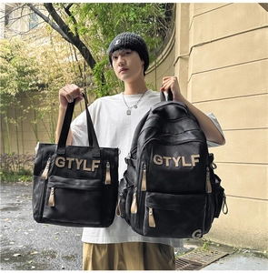 Photo en extérieur d'un ensemble sac à dos et cabas en toile noire avec écussons GTYLF