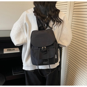 Detailed view of lightweight black nylon backpack featuring buckle and drawstring closure