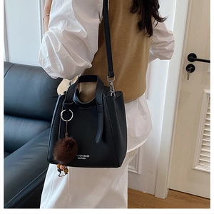 Détail d'un sac bandoulière vintage en cuir noir avec pompon porté par un mannequin