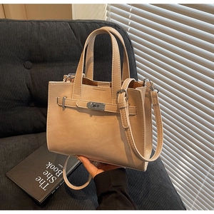 Detailed close-up of beige PU leather tote with classic metal lock and strap design