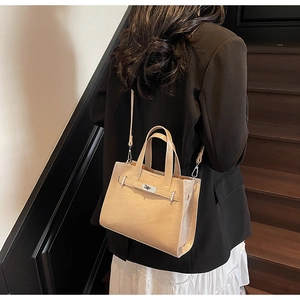 Detail of beige leather tote bag with classic metal twist lock and dual top handles