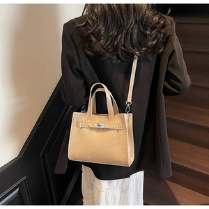Detail of elegant khaki leather tote with metal turn-lock and detachable strap on model