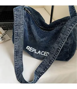 Detailed texture of blue washed denim shoulder bag featuring bold white REPLACED printed text