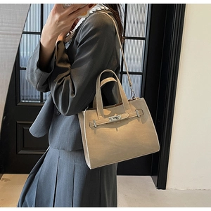 Detail view of khaki leather handbag with metal buckle and detachable shoulder strap