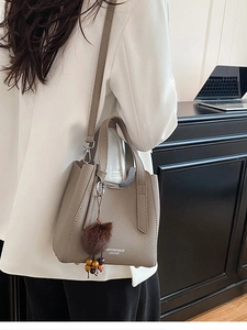 Sac seau rétro en cuir marron avec poignée supérieure et bandoulière dans un cadre professionnel