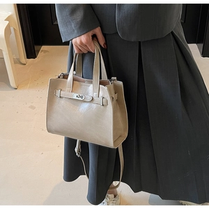 Detail of beige faux leather tote with metallic buckle and accordion side folds