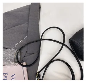 Detail of adjustable black litchi leather strap with gold metal buckle on bucket bag