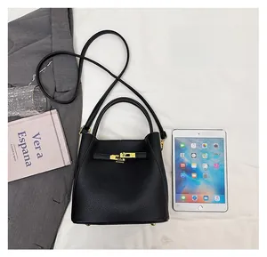 Detail of black pebbled leather bucket bag showing golden metal lock and internal capacity