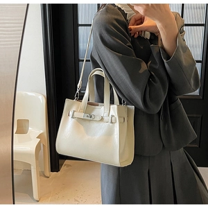 Detailed view of white leather handbag with elegant metal buckle and adjustable strap