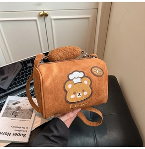 Detail of brown cylindrical crossbody bag with cute bear embroidery and fuzzy plush handle