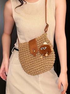 Handwoven straw crossbody bag with brown leather strap and cute pompom charm