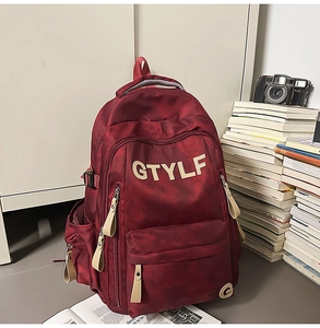 Vue détaillée du sac à dos en nylon rouge foncé avec poches et logo GTYLF brodé