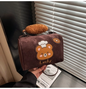 Detail of retro dark brown suede Boston bag with teddy bear embroidery and bread handle