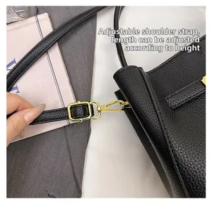 Detail of adjustable shoulder strap with gold metal buckle on black litchi leather bag