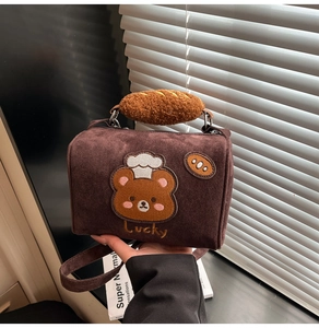 Detail of a brown suede mini bag featuring a chef bear patch and plush bread handle