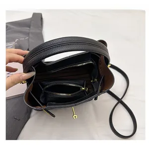 Close-up of black pebble leather bucket bag interior with brown liner and gold lock