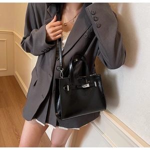 Detail of glossy black leather tote with silver twist lock and adjustable shoulder strap